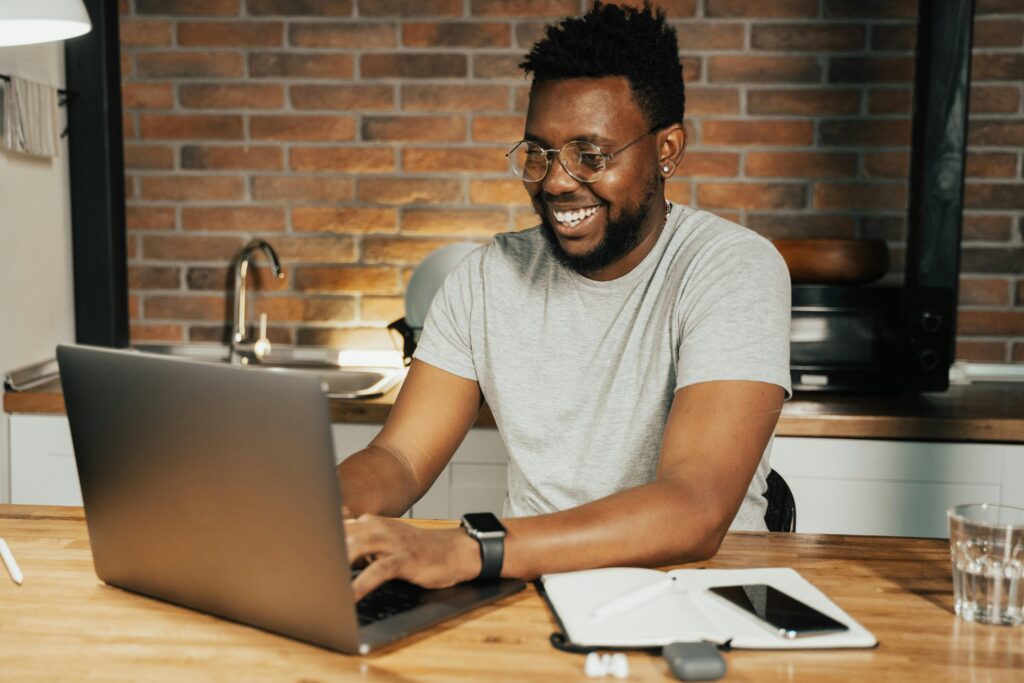 Man sitting behind his computer smiling and typing, as if responding to a pleasant email.