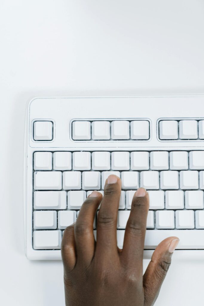 A man's left hand on a white keyboard